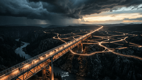 Illuminated bridge crossing a rugged canyon beneath dark storm clouds
